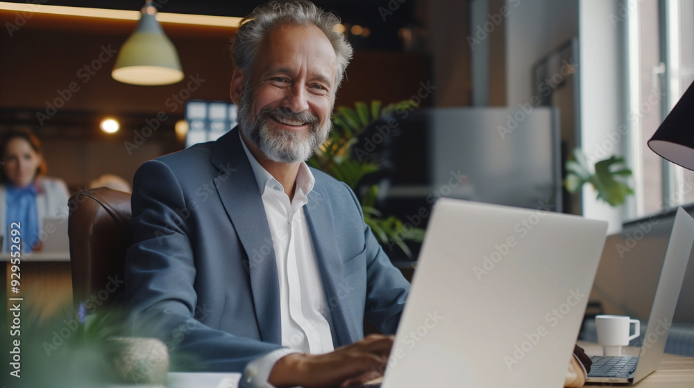 Smiling mature business executive using laptop in office professional corporate technology manager working at desk Smiling mature business executive using laptop in office professional corporate technology manager working at desk