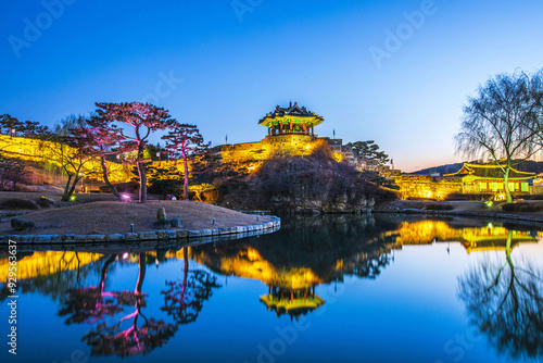 Suwon-si, Gyeonggi-do, South Korea - February 20, 2022: Winter and night view of Yongyeon Lake with pine and willow trees against Banghwasuryujeong Pavilion of Suwon Hwaseong Fortress photo