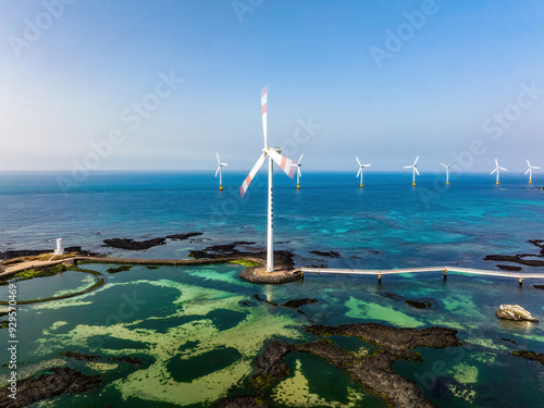 Singgyemul Park, Sinchang-ri, Hangyeong-myeon, Jeju-si, Jeju-do, South Korea - March 16, 2022: Aerial view of volcanic rocks and wind generators at Sinchang Coastal Road against turbins on the sea photo