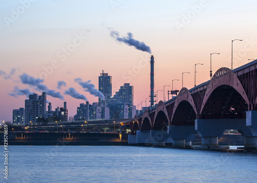 Mapo-gu, Seoul, South Korea - February 17, 2022: Sunset view of Seongsan Bridge on Han River against Mok-dong Thermal Power Plant with chimney and apartments photo