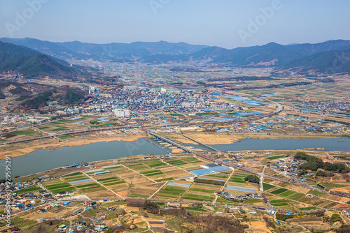 Gurye-gun, Jeollanam-do, South Korea - March 29, 2022: High angle and spring view of Seomjin River and houses of a village with rice paddy photo