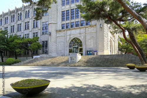 Hoegi-dong, Dongdaemun-gu, Seoul, South Korea - April 17, 2022: Spring view of square and a bronze statue sitting on stair at the entrance door of Central Library at Kyunghee University photo