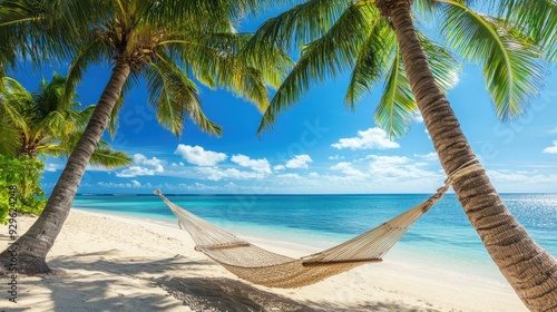 A serene beach scene with a hammock between palm trees under a clear blue sky.