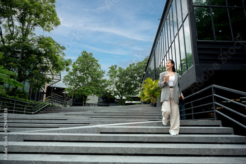 A young woman is walking down the stairs in front of a large glass building.