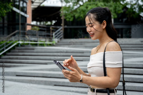Asian woman in a trendy outfit replying to a chat or using a mobile app.
