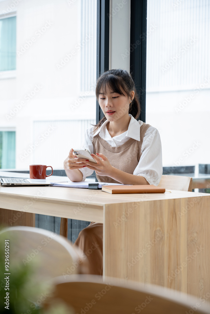 Asian businesswoman using a phone for work at her desk in an office. Asian businesswoman using a phone for work at her desk in an office.