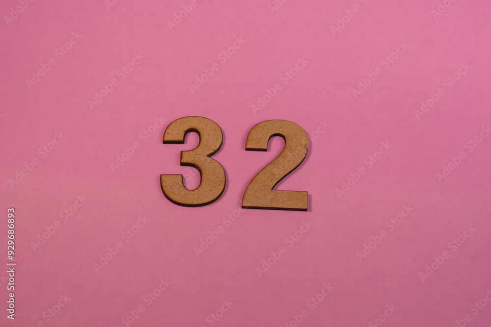 Number 32 in wood on a pink background Number 32 in wood on a pink background