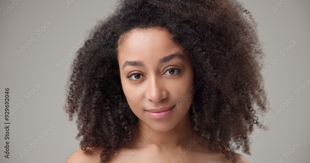 Beauty and healthcare concept - beautiful African American woman with curly afro hairstyle and clean, healthy skin looks at the camera with a calm look and a slight smile Beauty and healthcare concept - beautiful African American woman with curly afro hairstyle and clean, healthy skin looks at the camera with a calm look and a slight smile