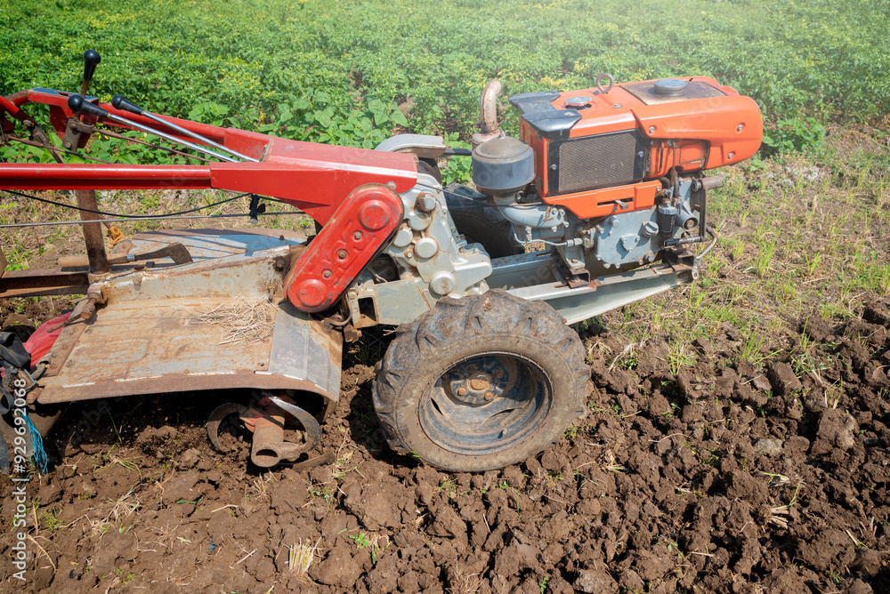 A tractor is working in a field with dirt and grass A tractor is working in a field with dirt and grass