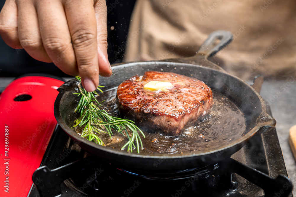 A person is cooking a tenderloin steak in a pan with butter and herbs A person is cooking a tenderloin steak in a pan with butter and herbs