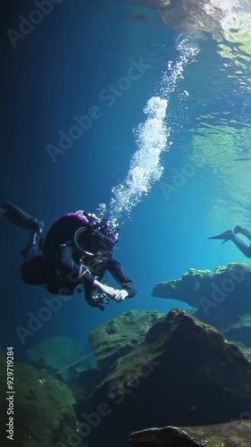 Wallpaper Mural A man is diving in the ocean wearing a black wetsuit. The water is blue and the man is surrounded by rocks Torontodigital.ca