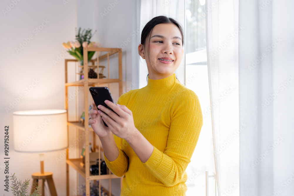 Happy young asian woman relax on comfortable couch at home texting messaging on smartphone, smiling girl use cellphone, chatting online message, shopping online from home
