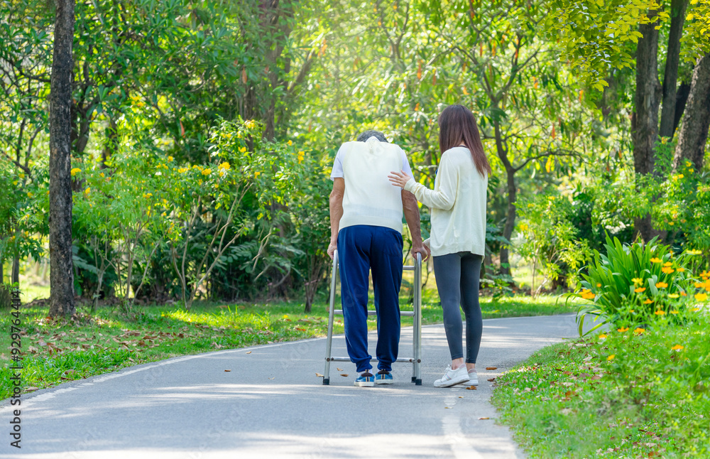 back view of daughter help disability father walking in the park,a young adult woman supporting a senior man using a walker to walk in the park back view of daughter help disability father walking in the park,a young adult woman supporting a senior man using a walker to walk in the park