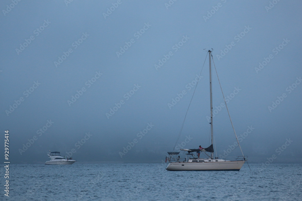 Fototapeta premium Foggy view of Sailboat on ocean with faint horizon