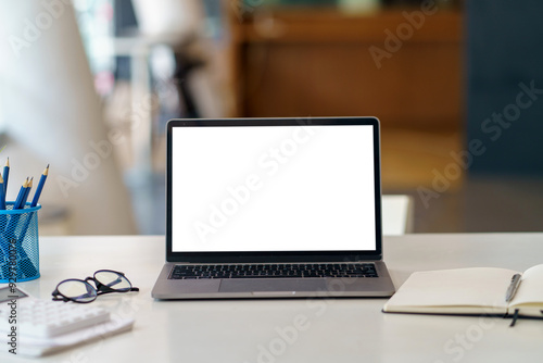 Workspace desk featuring an open laptop computer with a white screen, perfect for displaying your website or application