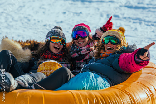 Three friends enjoying a fun day of tubing on snowy slopes during winter photo