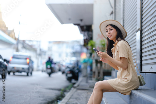 A woman in a yellow dress is sitting on a ledge with her cell phone in her hand photo