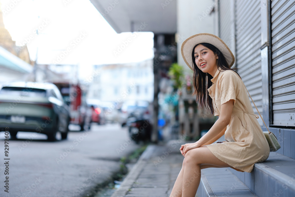 Fototapeta premium A woman in a yellow dress is sitting on a ledge in front of a car