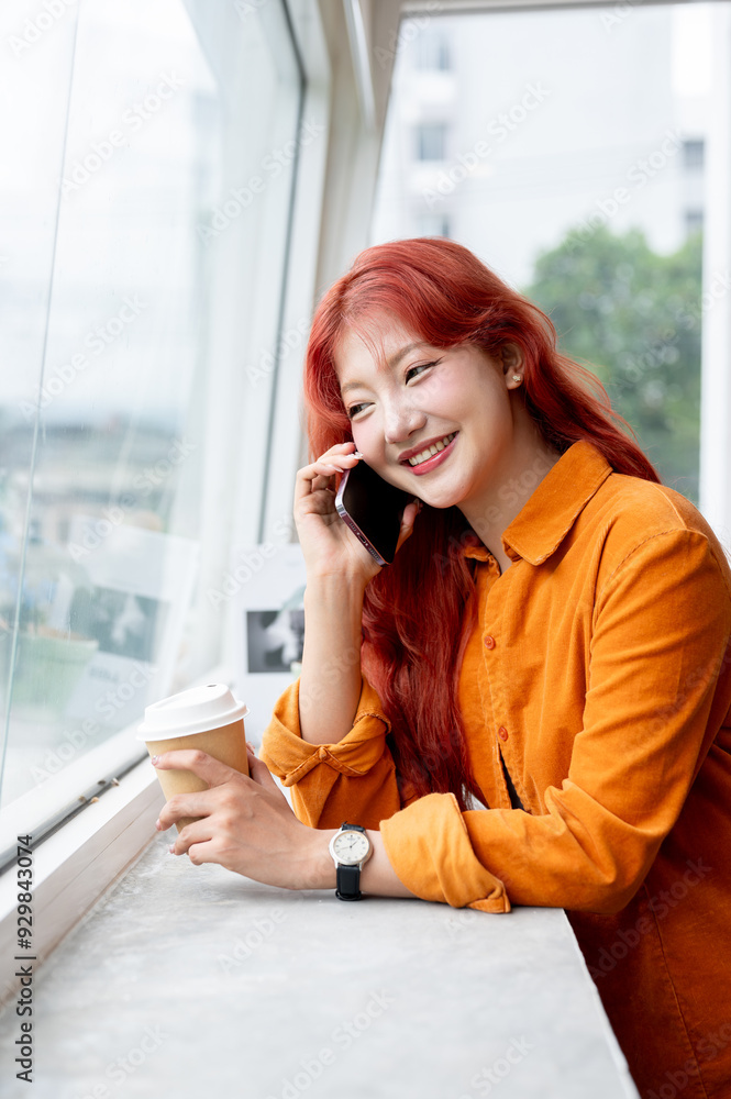 A beautiful Asian woman is talking on the phone while standing by the window. A beautiful Asian woman is talking on the phone while standing by the window.