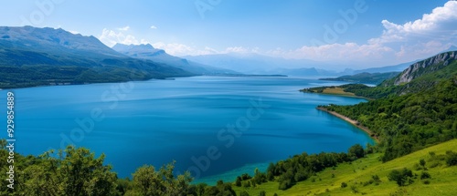  A large, tranquil lake encircled by verdant hills and a crystal-clear blue sky dotted with scattered clouds