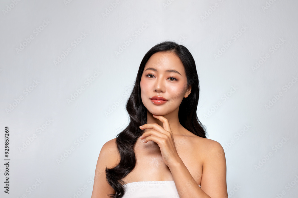 An elegant Asian woman poses with her hand on her chin against a grey background. An elegant Asian woman poses with her hand on her chin against a grey background.