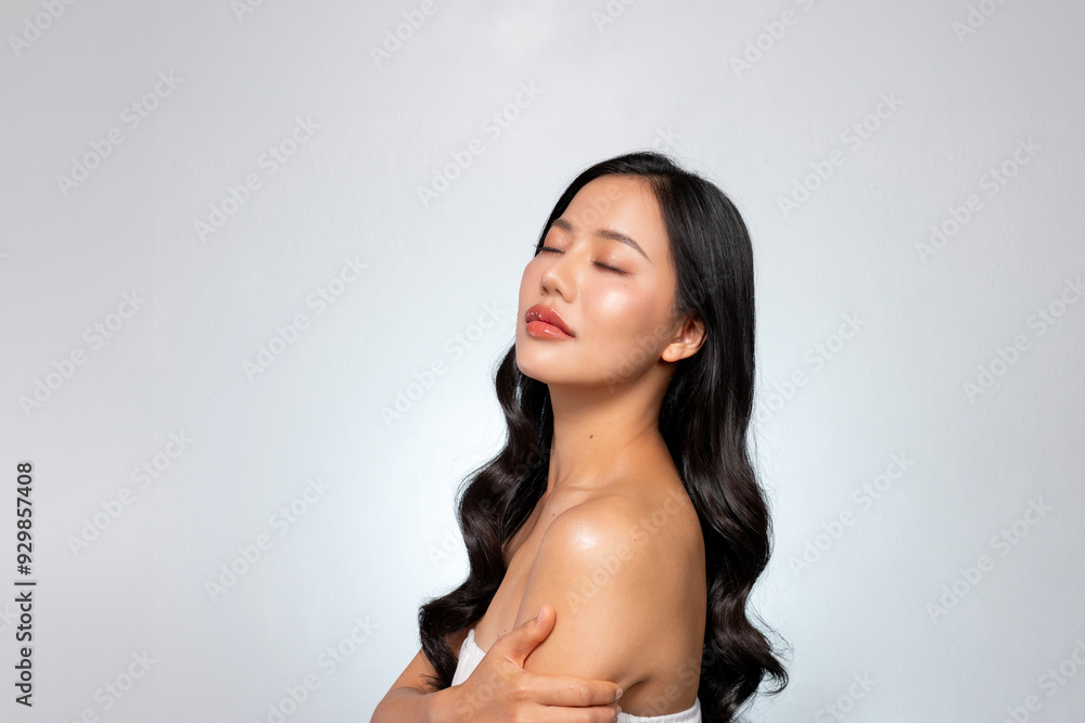 A young Asian woman with a perfect face poses, touching her shoulders with her eyes closed. A young Asian woman with a perfect face poses, touching her shoulders with her eyes closed.