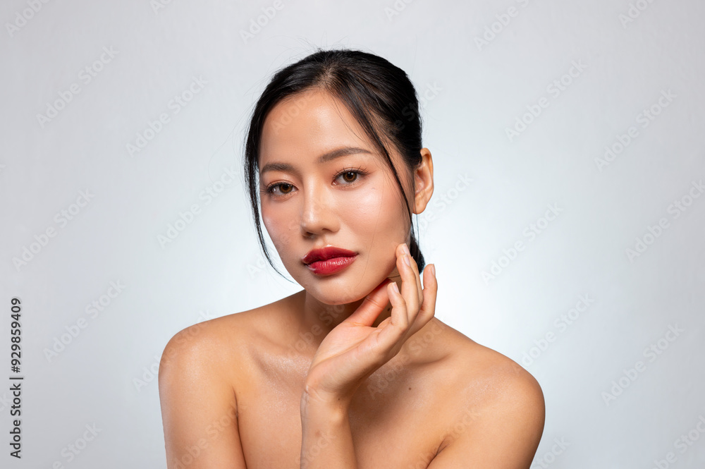 A beautiful Asian woman with red lips, and tanned skin poses against an isolated grey background. A beautiful Asian woman with red lips, and tanned skin poses against an isolated grey background.