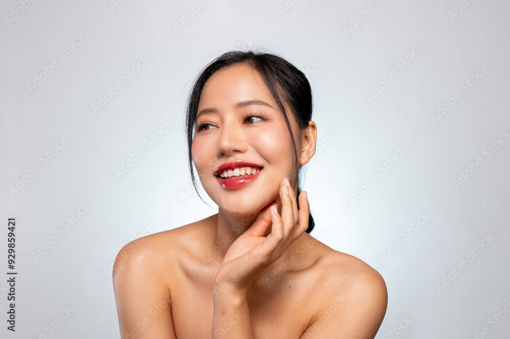 A pretty Asian woman poses against a grey studio background, smiles with her teeth visible. A pretty Asian woman poses against a grey studio background, smiles with her teeth visible.