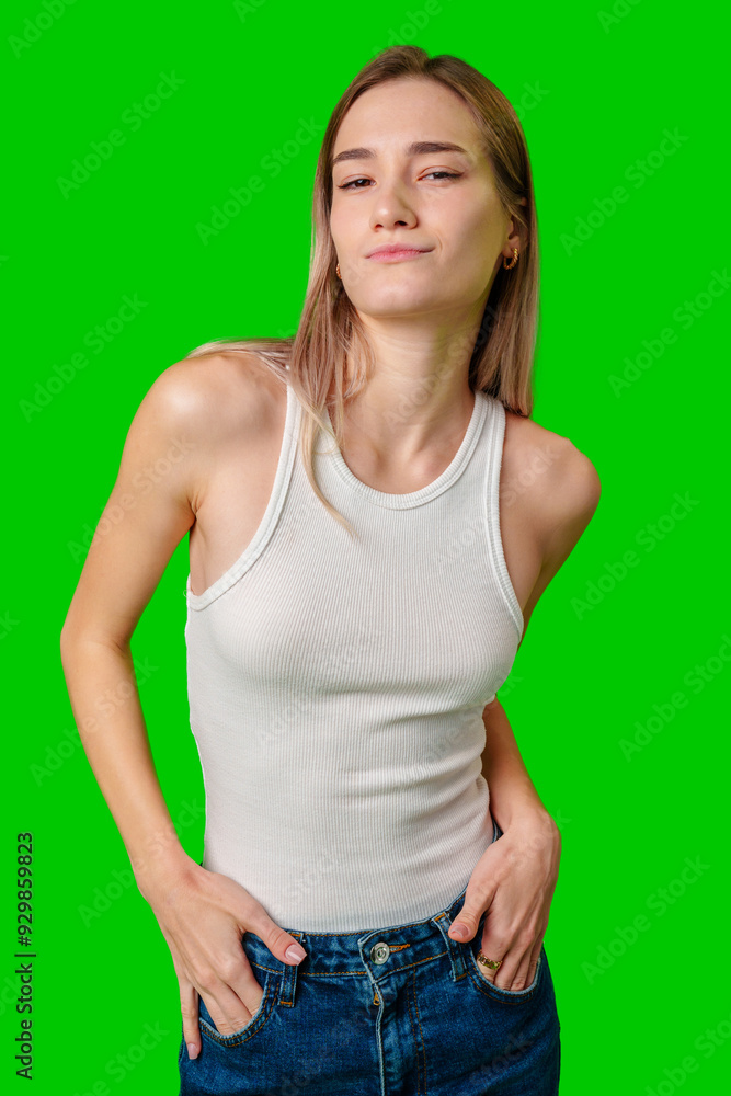 Young Woman Posing in White Tank Top and Jeans Against Green Screen Young Woman Posing in White Tank Top and Jeans Against Green Screen