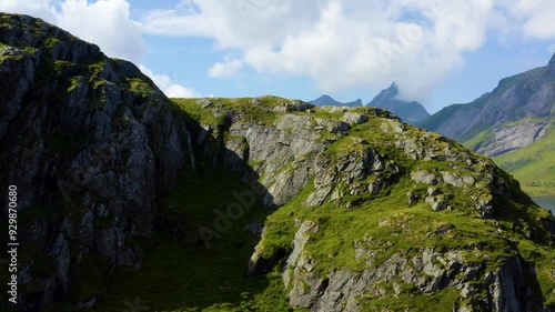 Drone ascends lush green hillside cliff to establish breathtaking stunning view of Selfjord in Lofoten Norway with grand sharp rugged mountain peaks photo