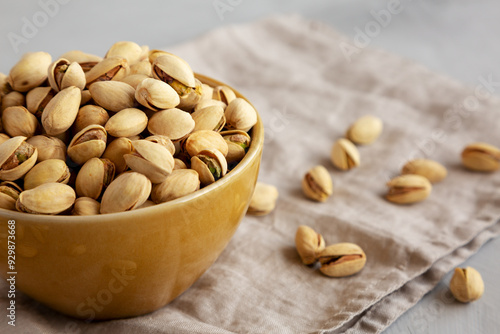 Roasted and Salted Pistachios in a Bowl on a gray background, side view.