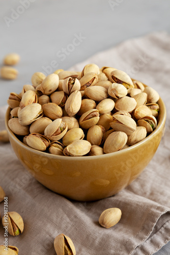Roasted and Salted Pistachios in a Bowl on a gray background, side view.