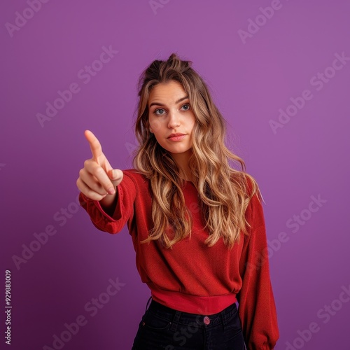 Wallpaper Mural A beautiful young woman pointing outward at the viewer, isolated on a vibrant purple background.  Torontodigital.ca