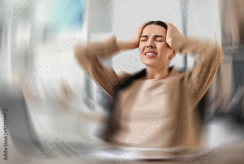 Woman suffering from headache indoors, motion blur effect photo