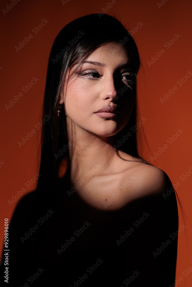 Brunette girl posing in a beam of light in the studio, on a red background, light and darkness. Brunette girl posing in a beam of light in the studio, on a red background, light and darkness.
