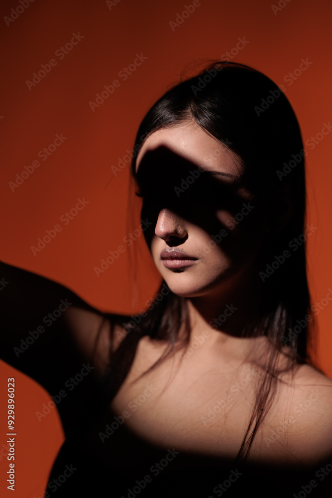 Brunette girl posing in a beam of light in the studio, on a red background, light and darkness. Brunette girl posing in a beam of light in the studio, on a red background, light and darkness.