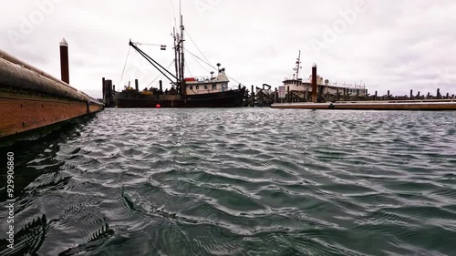 Bird flies over two boats docked at a pier photo