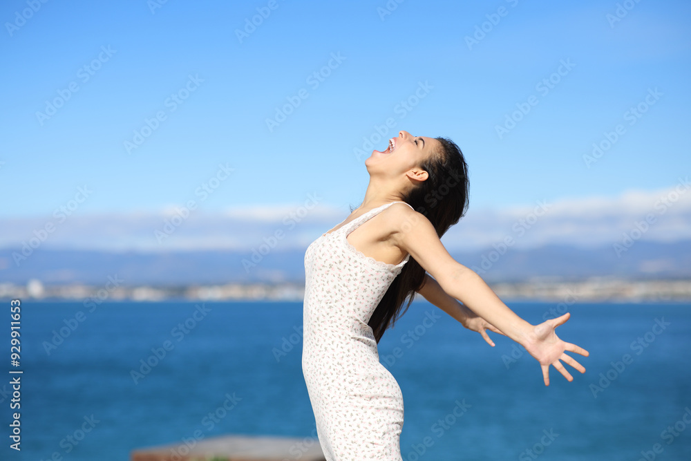 Excited woman screaming celebrating vacation on the beach