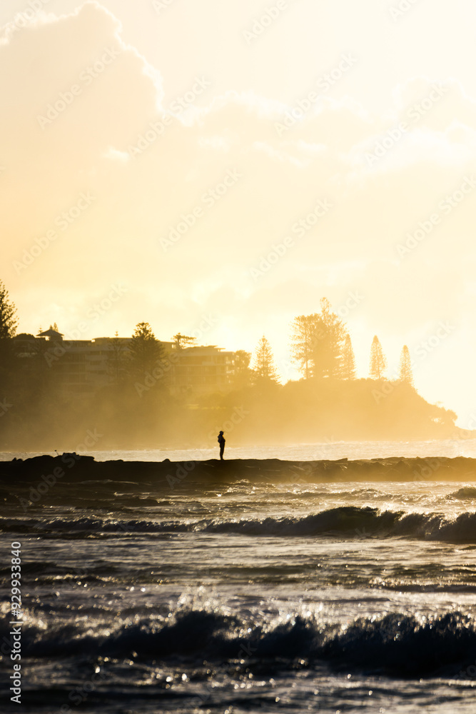 Fototapeta premium human standing in the ocean steam in the distance at sunrise