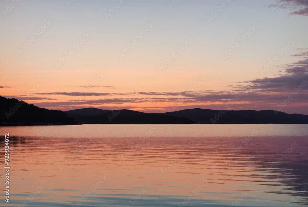 Obraz premium Clear blue sky sunset with glowing pink and purple horizon on calm ocean seascape background. Water surface texture. Picturesque dreamlike seascape, clouds-cape, nature. Panoramic view