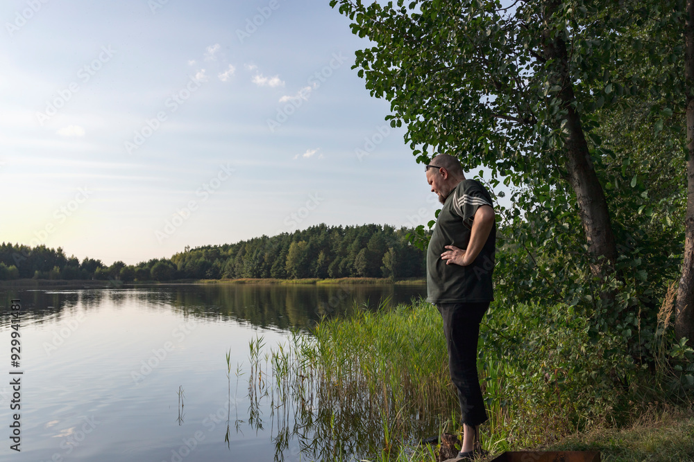 A man stands on a dock overlooking a lake A man stands on a dock overlooking a lake