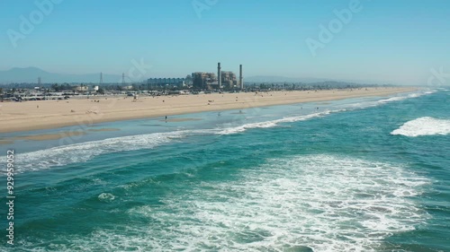 Flying low, over the blue Huntington Beach water towards the power plant beyond