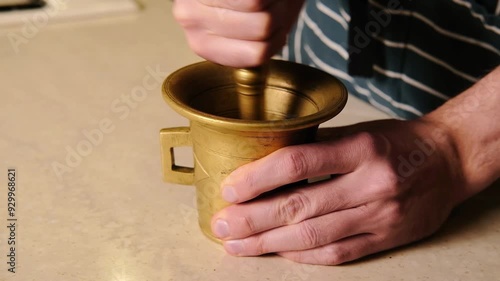 Man grinding spices in a bronze mortar 4k video, close up