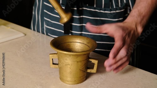 Man grinding spices in a bronze mortar 4k video, close up