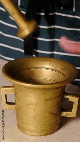 Man grinding spices in a bronze mortar 4k video, close up,  vertical video
