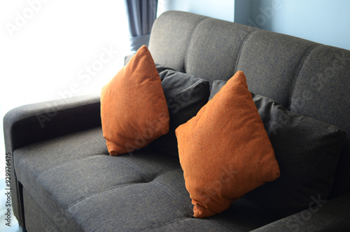 Gray sofa and orange cushions There was light shining beside the door.