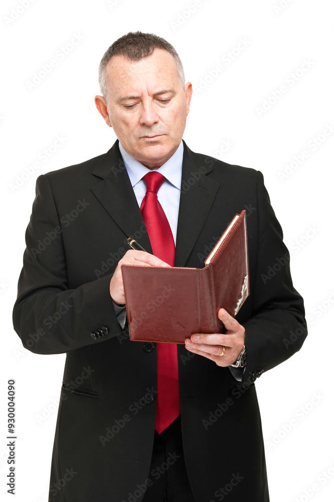 Mature businessman in a suit focused on reading his brown notebo Mature businessman in a suit focused on reading his brown notebo