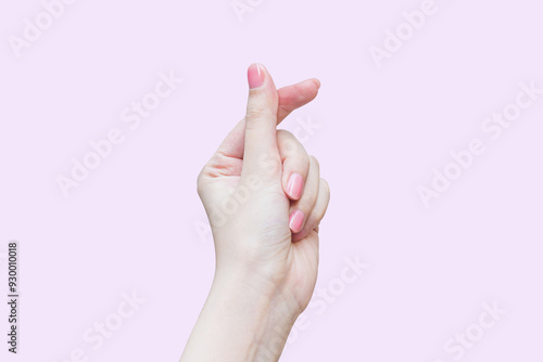 Beautiful female hand shows finger and hand like mini heart shape Korea style as a sign of love while isolated on pink background.