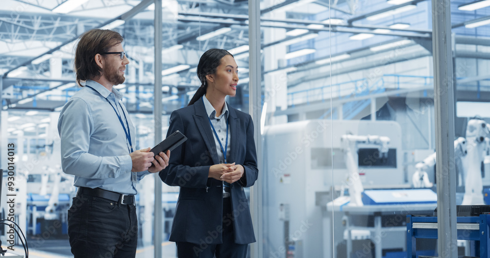 Two Diverse Engineers Walking in Office, Using Tablet Computer at an Electronics Factory. Female and Male Specialists Chatting, Monitoring Robots on Modern Assembly Line. Two Diverse Engineers Walking in Office, Using Tablet Computer at an Electronics Factory. Female and Male Specialists Chatting, Monitoring Robots on Modern Assembly Line.