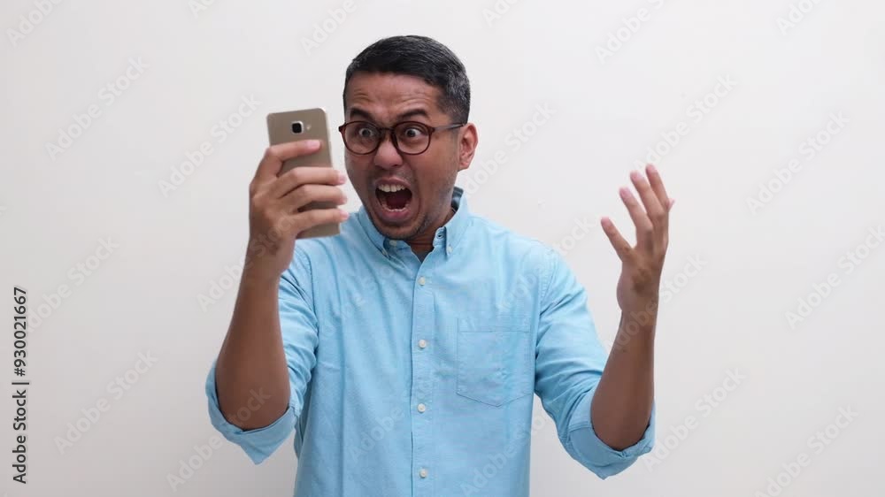 A man showing angry and frustrated when looking to his mobile phone A man showing angry and frustrated when looking to his mobile phone